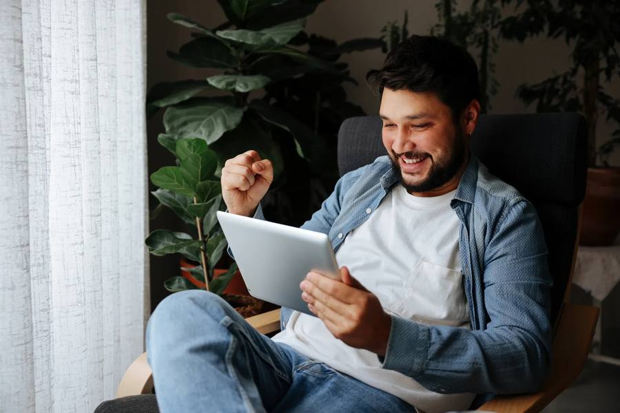 Man celebrating results while looking at a tablet